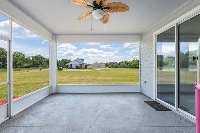 unfurnished sunroom featuring ceiling fan and plenty of natural light