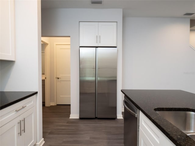 kitchen with white cabinets, dark hardwood / wood-style flooring, stainless steel appliances, and dark stone counters