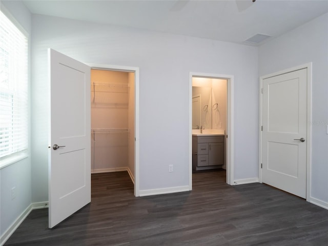 unfurnished bedroom featuring dark hardwood / wood-style floors, a closet, a spacious closet, and ensuite bathroom