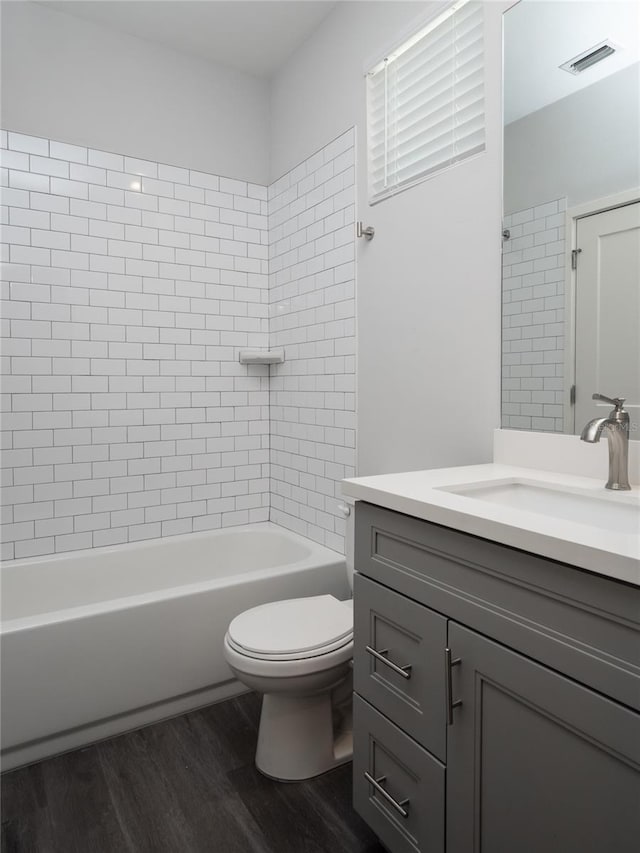 full bathroom featuring toilet, vanity, wood-type flooring, and tiled shower / bath