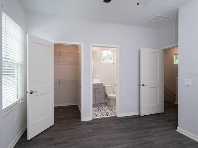 unfurnished bedroom with dark hardwood / wood-style floors, ceiling fan, a closet, connected bathroom, and a walk in closet