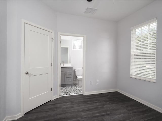 unfurnished bedroom with connected bathroom and dark hardwood / wood-style floors