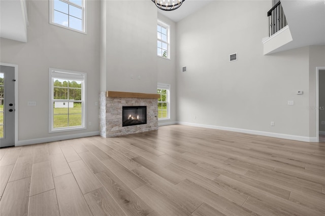 unfurnished living room with a fireplace, a towering ceiling, and light wood-type flooring