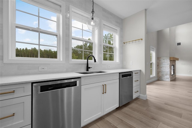 kitchen with white cabinets, dishwasher, light hardwood / wood-style flooring, and sink