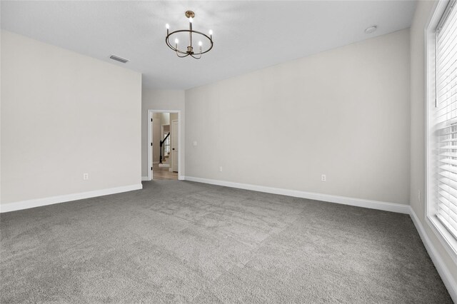 unfurnished room featuring a chandelier, carpet flooring, and a wealth of natural light