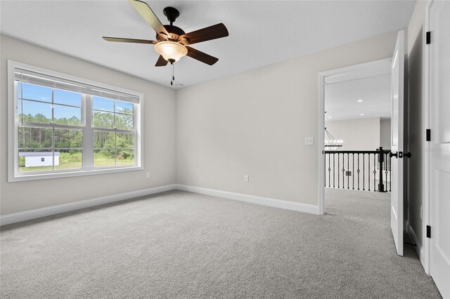 spare room featuring light carpet and ceiling fan with notable chandelier