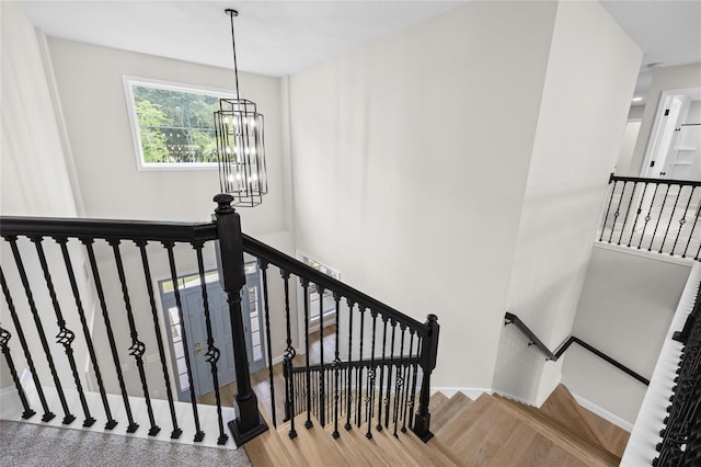 stairway with light hardwood / wood-style floors and a notable chandelier