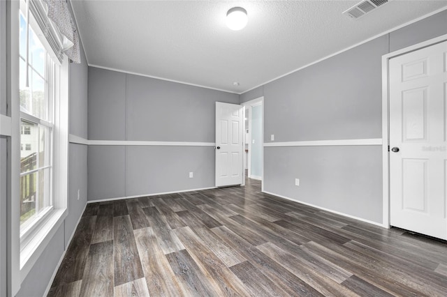 spare room featuring a textured ceiling, crown molding, hardwood / wood-style floors, and plenty of natural light