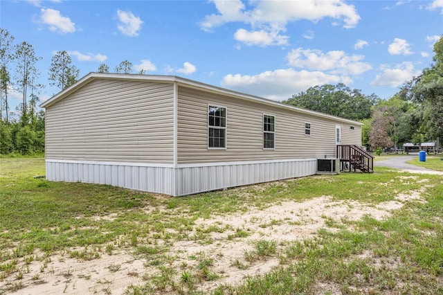 view of property exterior with central AC unit and a yard