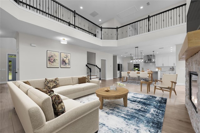 living room featuring a high ceiling, a fireplace, and light hardwood / wood-style flooring