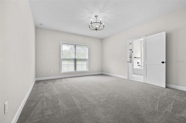 carpeted spare room featuring a chandelier