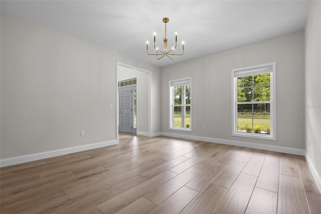 empty room featuring an inviting chandelier and wood-type flooring