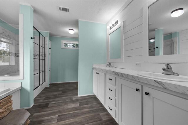 bathroom with a textured ceiling, double vanity, shower with separate bathtub, hardwood / wood-style floors, and ornamental molding