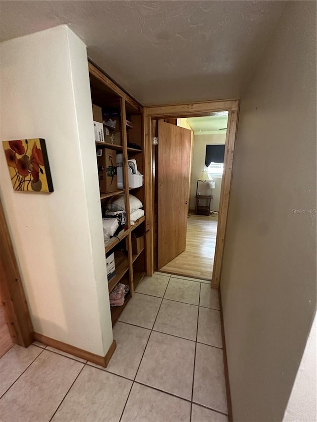 corridor with light tile patterned flooring and a textured ceiling