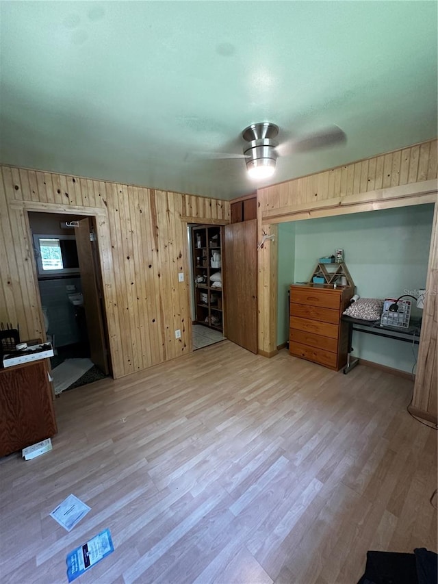 bedroom featuring light hardwood / wood-style flooring, ceiling fan, and wood walls