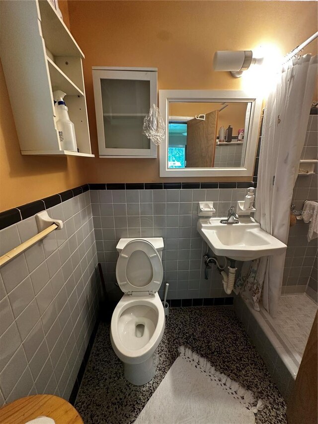 4215 NW 10th St, Gainesville, FL 32609 - full bathroom featuring tile walls, toilet, a tile shower, wainscoting, and a sink