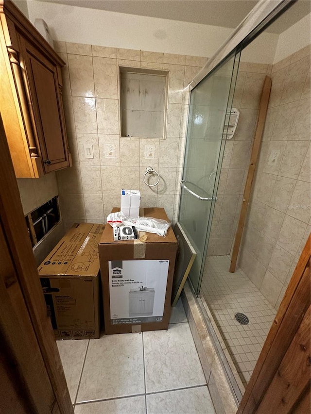 bathroom featuring tile walls, a shower with door, and tile patterned floors