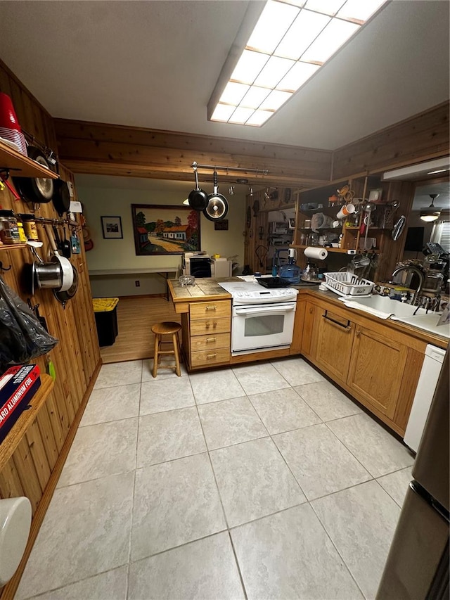 kitchen with sink, tile countertops, light tile patterned floors, wooden walls, and electric stove