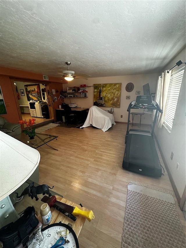 living room with ceiling fan, wood-type flooring, and a textured ceiling