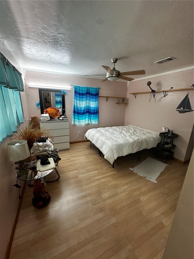 bedroom featuring ceiling fan, a textured ceiling, and light hardwood / wood-style floors