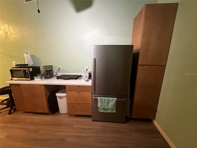 kitchen featuring dark wood-type flooring, stainless steel fridge, a kitchen breakfast bar, and kitchen peninsula