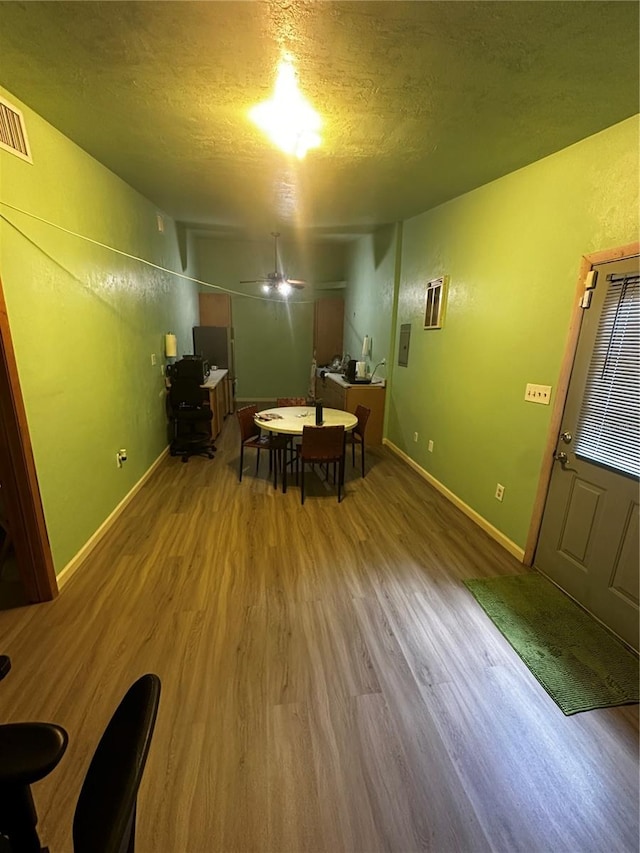 unfurnished dining area featuring ceiling fan, hardwood / wood-style flooring, and a textured ceiling