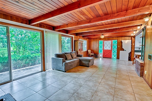 unfurnished living room with light tile patterned floors, wooden walls, wooden ceiling, ceiling fan, and beam ceiling