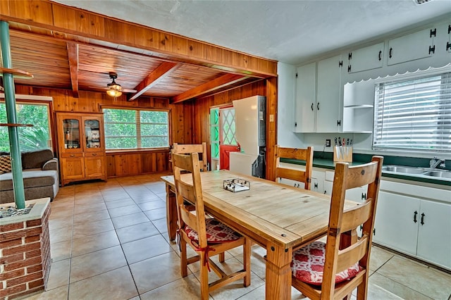 tiled dining room with ceiling fan, sink, beamed ceiling, and a healthy amount of sunlight