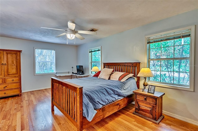 bedroom with ceiling fan, multiple windows, and light hardwood / wood-style floors