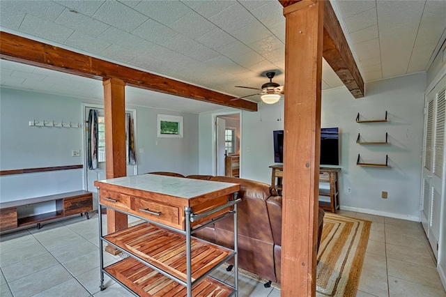 tiled dining room with ceiling fan and beamed ceiling