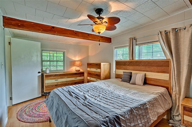 bedroom with ceiling fan, multiple windows, beam ceiling, and hardwood / wood-style floors