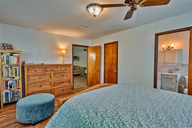 bedroom with ceiling fan, sink, connected bathroom, and light hardwood / wood-style floors