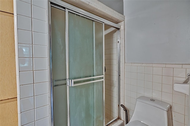 bathroom with tile walls, toilet, and walk in shower