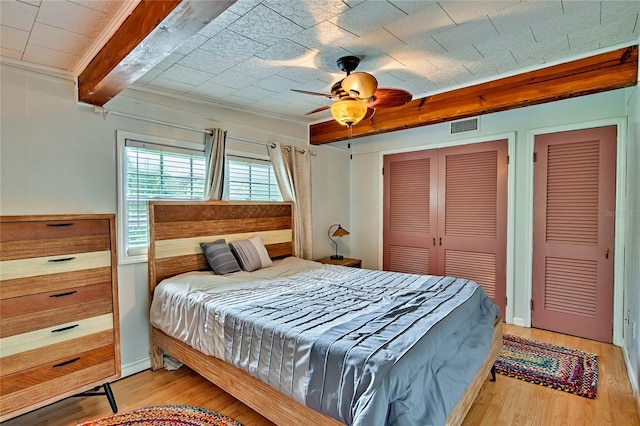 bedroom featuring light wood-type flooring, ceiling fan, crown molding, and beamed ceiling