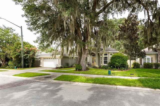 obstructed view of property featuring a garage, stucco siding, concrete driveway, and a front yard