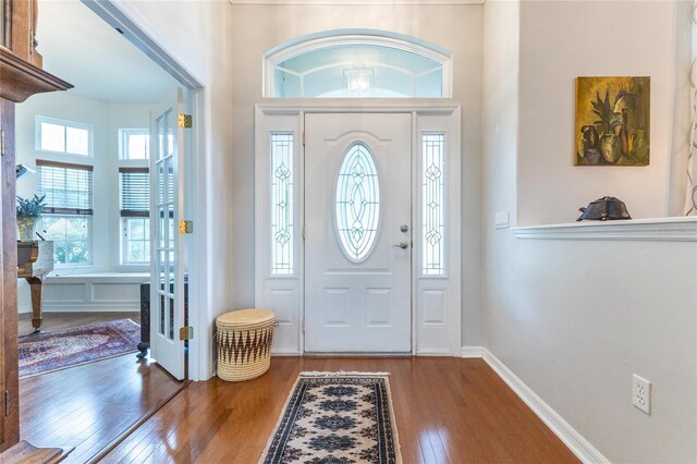 foyer with hardwood / wood-style flooring, plenty of natural light, and a high ceiling