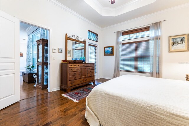 bedroom featuring ornamental molding, ceiling fan, dark hardwood / wood-style floors, and a tray ceiling