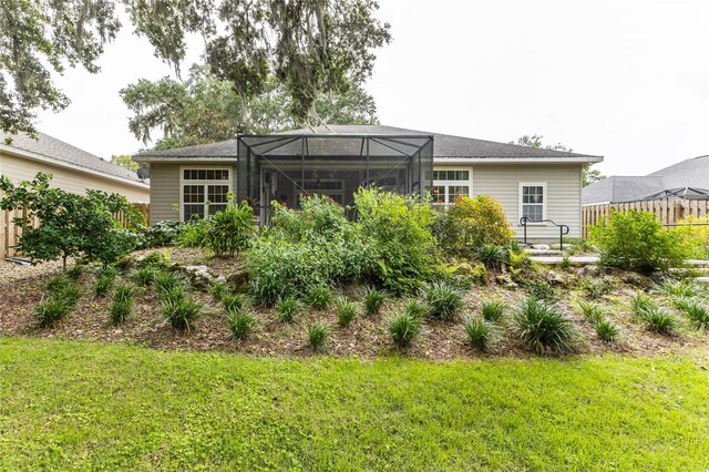 back of house with a lawn and glass enclosure