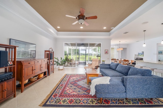 tiled living room featuring ceiling fan, a tray ceiling, and ornamental molding