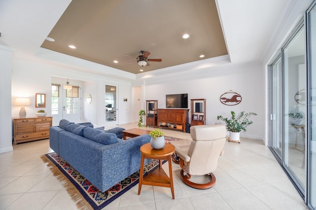 living room with a raised ceiling, light tile patterned floors, ceiling fan, and ornamental molding