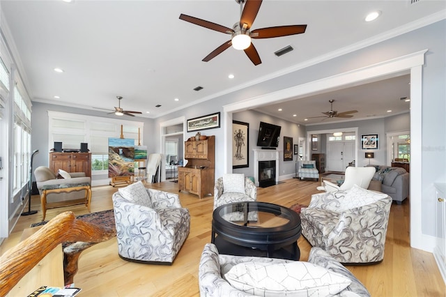 living room featuring ornamental molding, a glass covered fireplace, and visible vents