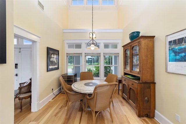 dining room with light wood-type flooring and a high ceiling