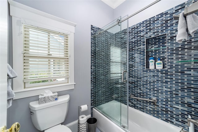 bathroom featuring bath / shower combo with glass door, plenty of natural light, and toilet