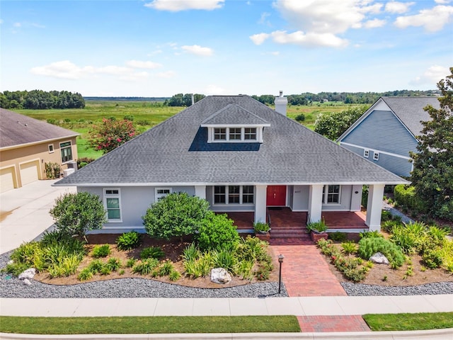 view of front of house featuring a garage, a shingled roof, a chimney, a porch, and stucco siding