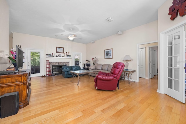 living room featuring light wood-type flooring, ceiling fan, and french doors