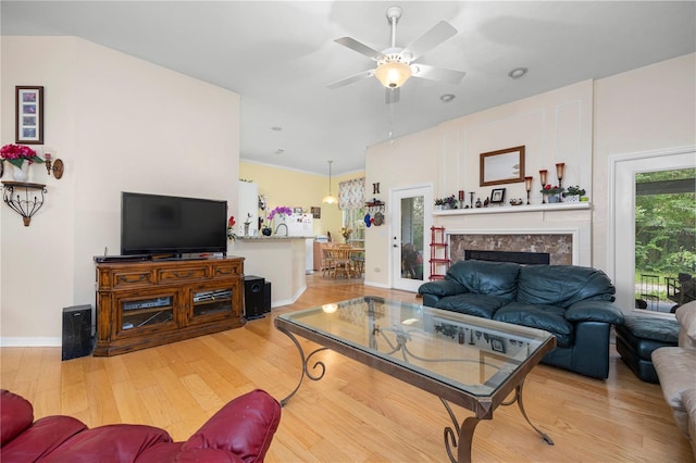 living room with ceiling fan, a fireplace, and light hardwood / wood-style flooring