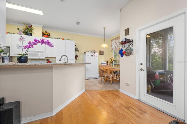 kitchen with white appliances, pendant lighting, crown molding, light tile patterned flooring, and white cabinetry