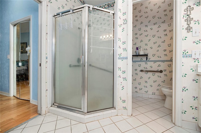 bathroom featuring hardwood / wood-style flooring, a shower with shower door, and toilet