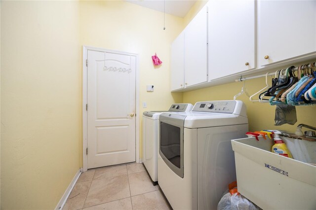 clothes washing area featuring sink, washing machine and dryer, cabinets, and light tile patterned floors