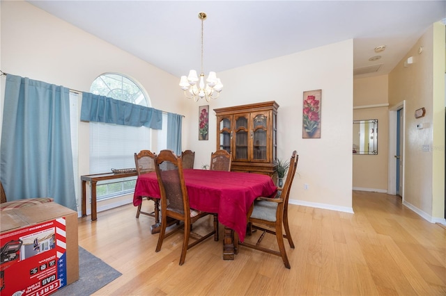 dining room with light hardwood / wood-style flooring and an inviting chandelier